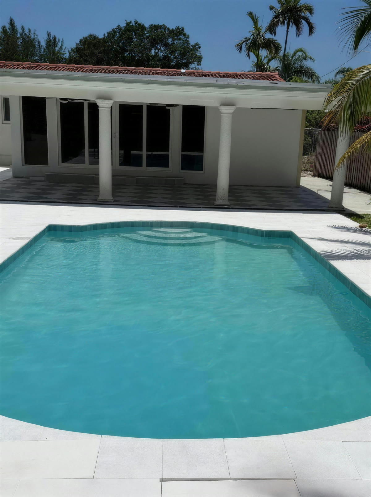 Resurfaced swimming pool with turquoise water and travertine deck